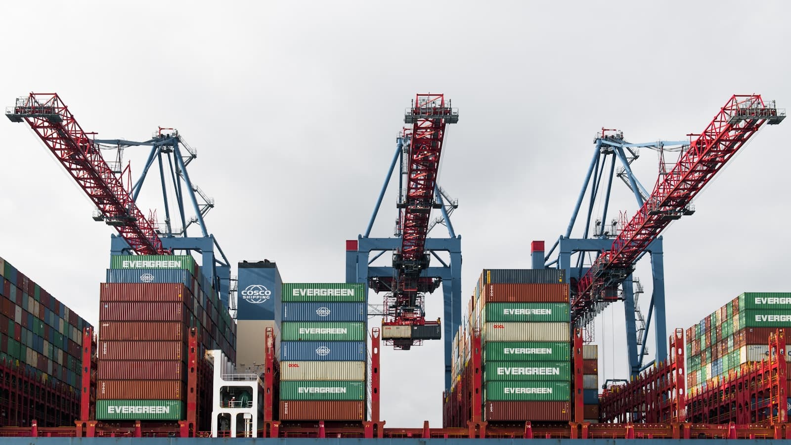 Gantry cranes loading shipping containers onto a large vessel at a terminal